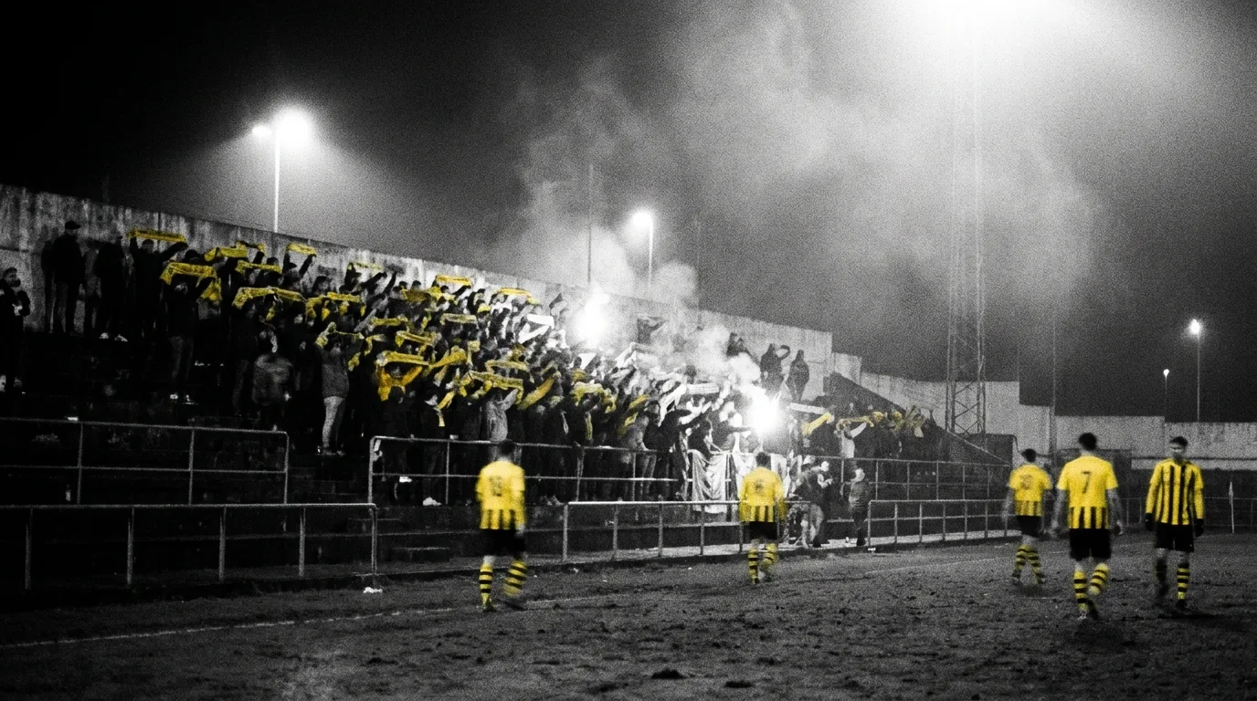 Fondo de pie del Campo do Peirao de noche, aficionados con bufandas amarillas en alto bajo los focos.